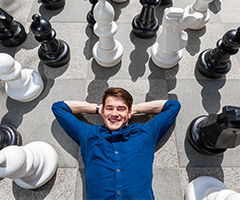 UCD student surrounded by chess pieces.